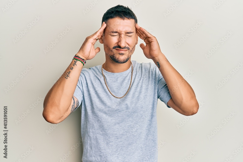 Handsome man with tattoos wearing casual 90s style and gold chain with hand on head, headache because stress. suffering migraine. Handsome man with tattoos wearing casual 90s style and gold chain with hand on head, headache because stress. suffering migraine.