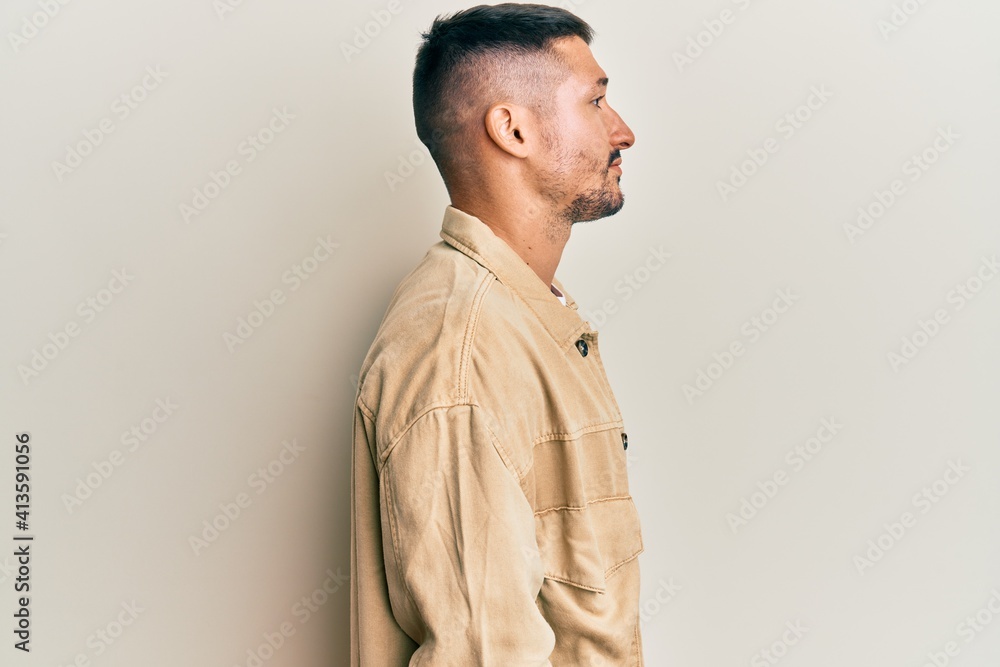Handsome man with tattoos wearing casual brown denim jacket looking to side, relax profile pose with natural face with confident smile. Handsome man with tattoos wearing casual brown denim jacket looking to side, relax profile pose with natural face with confident smile.