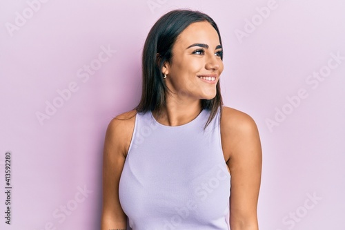 Young brunette woman wearing casual clothes looking to side, relax profile pose with natural face and confident smile.