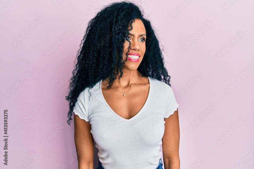 Middle age african american woman wearing casual white t shirt looking to side, relax profile pose with natural face and confident smile. Middle age african american woman wearing casual white t shirt looking to side, relax profile pose with natural face and confident smile.