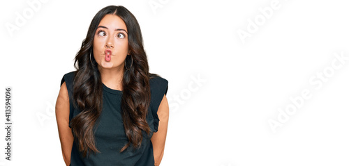 Foto Beautiful brunette young woman wearing black shirt making fish face with lips, crazy and comical gesture