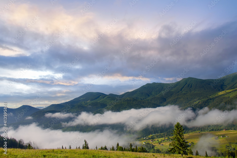 Beautiful clouds at dawn over the mountain tops. Calm summer morning in the mountains