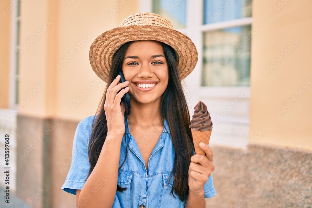 Young latin tourist girl on vacation talking on the smartphone and eating ice cream at the city.