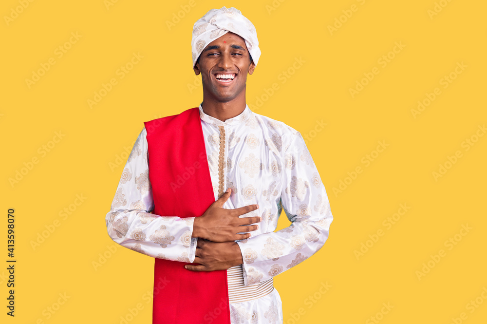 African handsome man wearing tradition sherwani saree clothes smiling and laughing hard out loud because funny crazy joke with hands on body. African handsome man wearing tradition sherwani saree clothes smiling and laughing hard out loud because funny crazy joke with hands on body.