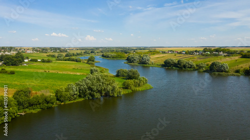 The river flows through the countryside surrounded by green meadows in the summer.