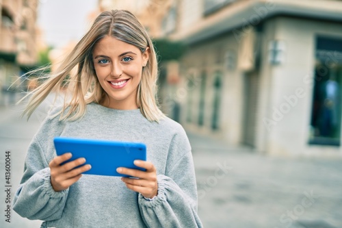 Young blonde girl smiling happy using touchpad at the city. © Krakenimages.com