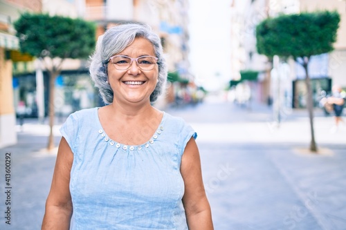 Middle age woman with grey hair smiling happy outdoors