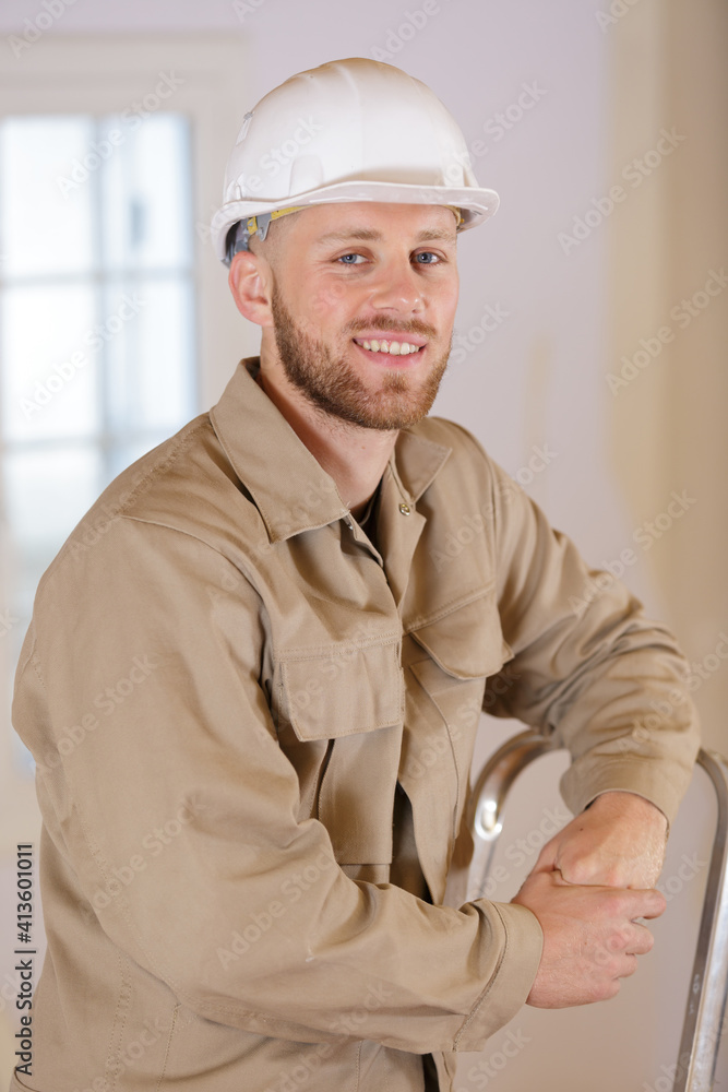 young builder leaning on a stepladder young builder leaning on a stepladder