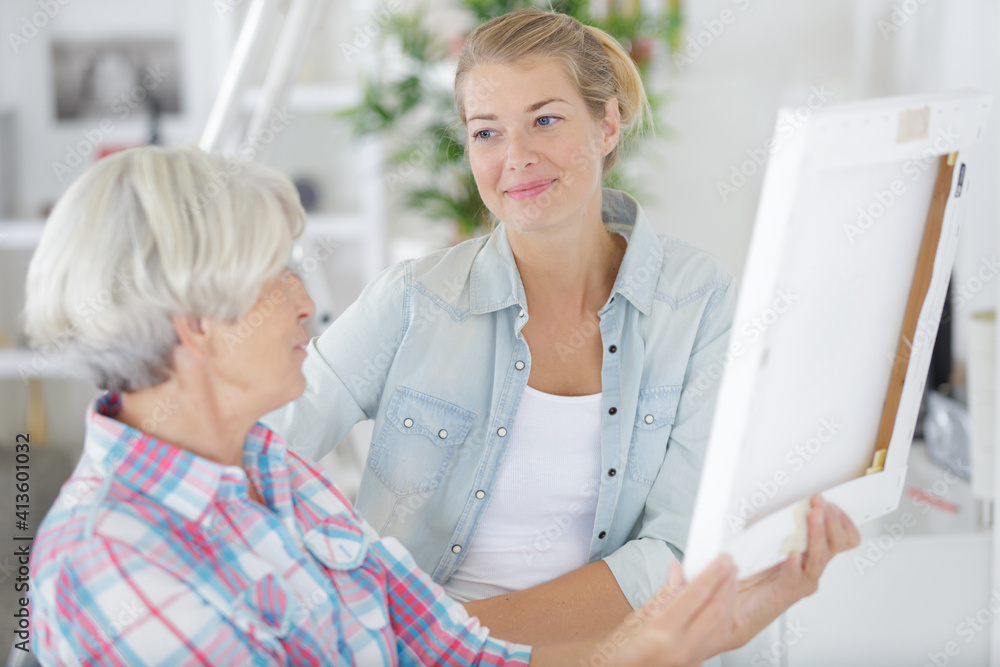 senior woman looks at photo in frame with daughter senior woman looks at photo in frame with daughter