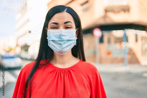 Young latin girl wearing medical mask walking at the city.