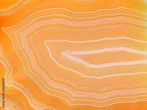 Amazing Banded Agate Crystal cross section as a background. Natural light translucent agate crystal surface. Yellow orange abstract expressive structure slice mineral stone macro closeup