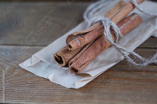 Cinnamon sticks lie on paper on a wooden table. Cinnamon sticks tied with rope. photo