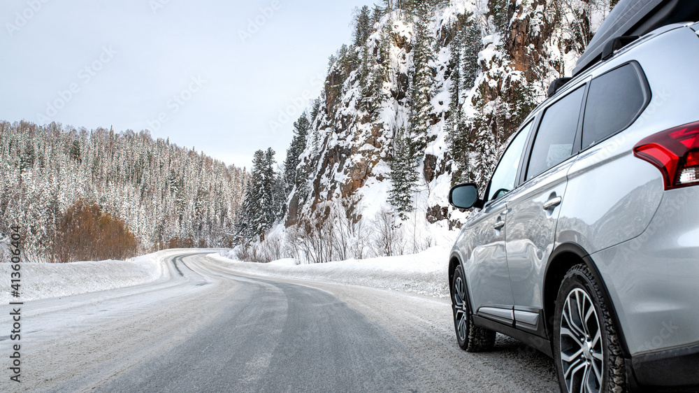 Suv car with rooftop cargo carrier trunk stay on roadside of winter road. Family trip to ski resort. Winter holidays adventure. car on winter road