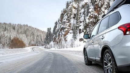 Suv car with rooftop cargo carrier trunk stay on roadside of winter road. Family trip to ski resort. Winter holidays adventure. car on winter road