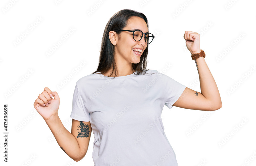 Young hispanic woman wearing casual white t shirt dancing happy and cheerful, smiling moving casual and confident listening to music Young hispanic woman wearing casual white t shirt dancing happy and cheerful, smiling moving casual and confident listening to music