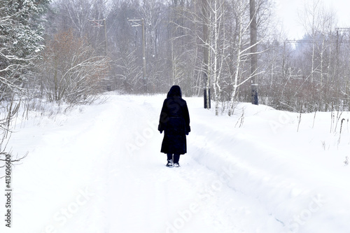A woman in a black fur coat walks the road covered with snow. © Михаил Жигалин