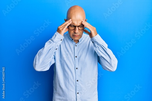 Middle age bald man wearing casual clothes and glasses with hand on head for pain in head because stress. suffering migraine.