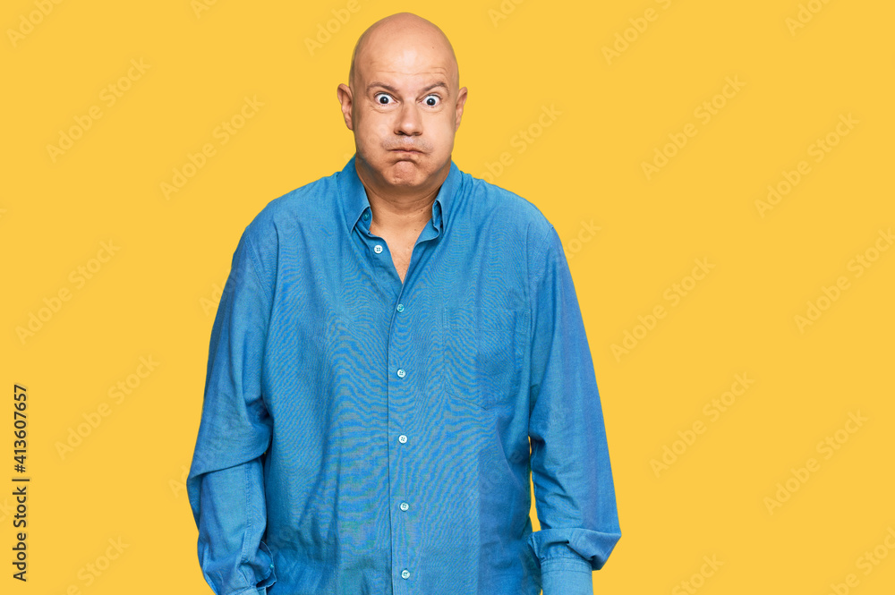 Middle age bald man wearing casual clothes puffing cheeks with funny face. mouth inflated with air, crazy expression. Middle age bald man wearing casual clothes puffing cheeks with funny face. mouth inflated with air, crazy expression.