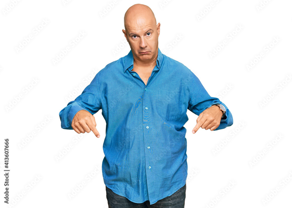 Middle age bald man wearing casual clothes pointing down looking sad and upset, indicating direction with fingers, unhappy and depressed. Middle age bald man wearing casual clothes pointing down looking sad and upset, indicating direction with fingers, unhappy and depressed.