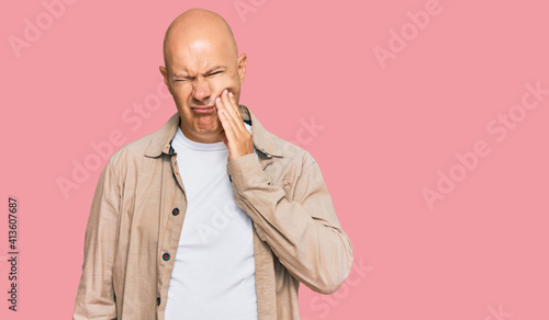 Middle age bald man wearing casual clothes touching mouth with hand with painful expression because of toothache or dental illness on teeth. dentist