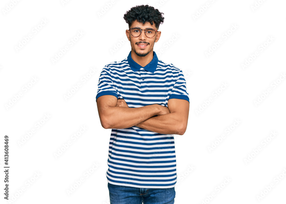 Young arab man wearing casual clothes and glasses happy face smiling with crossed arms looking at the camera. positive person. Young arab man wearing casual clothes and glasses happy face smiling with crossed arms looking at the camera. positive person.