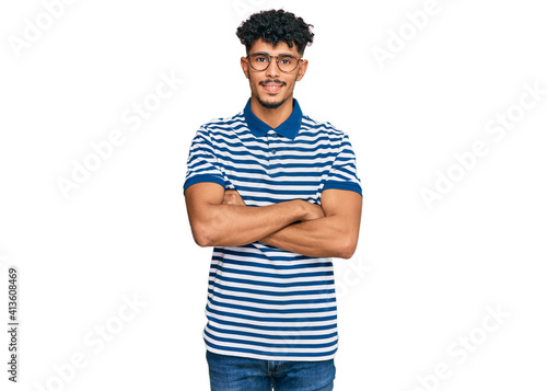 Young arab man wearing casual clothes and glasses happy face smiling with crossed arms looking at the camera. positive person. photo