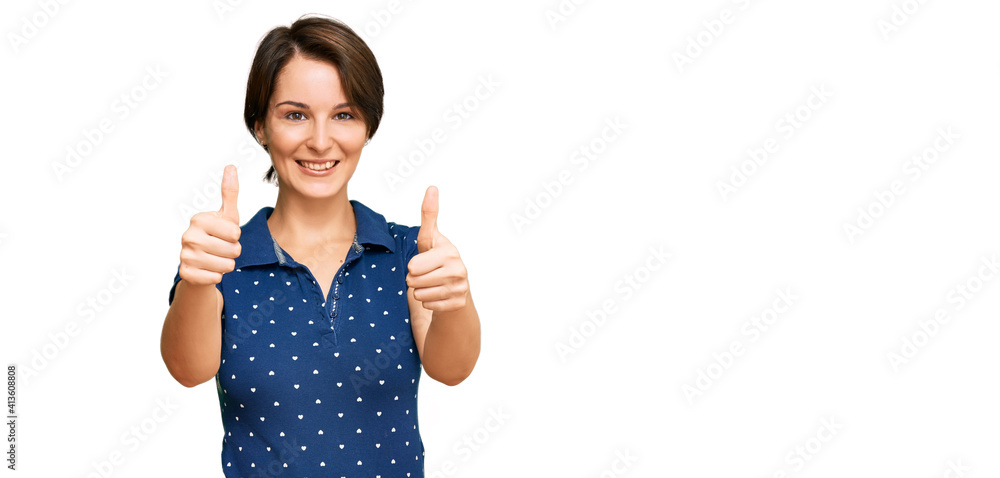 Young brunette woman with short hair wearing casual clothes approving doing positive gesture with hand, thumbs up smiling and happy for success. winner gesture. Young brunette woman with short hair wearing casual clothes approving doing positive gesture with hand, thumbs up smiling and happy for success. winner gesture.