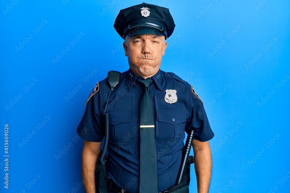 Handsome middle age mature man wearing police uniform puffing cheeks with funny face. mouth inflated with air, crazy expression. Handsome middle age mature man wearing police uniform puffing cheeks with funny face. mouth inflated with air, crazy expression.