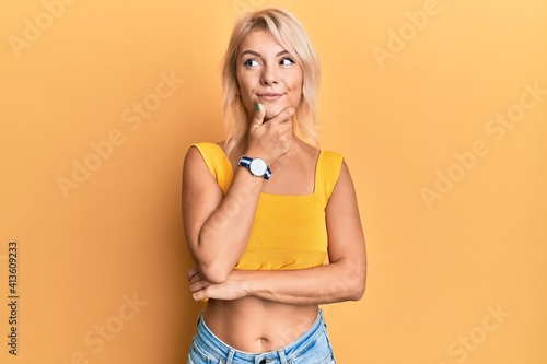 Young blonde girl wearing casual clothes with hand on chin thinking about question, pensive expression. smiling and thoughtful face. doubt concept. © Krakenimages.com