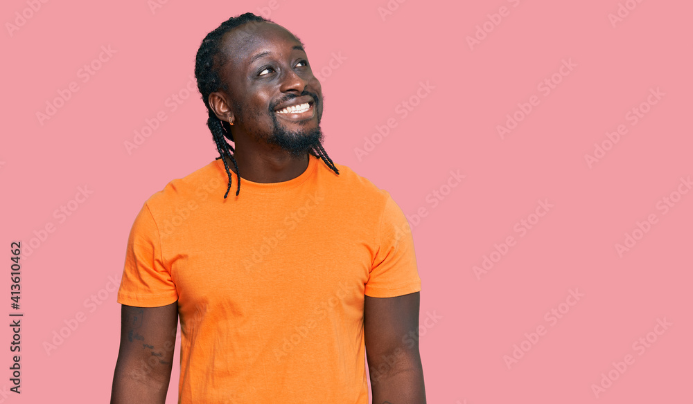 Handsome young african american man wearing casual clothes looking away to side with smile on face, natural expression. laughing confident. Handsome young african american man wearing casual clothes looking away to side with smile on face, natural expression. laughing confident.