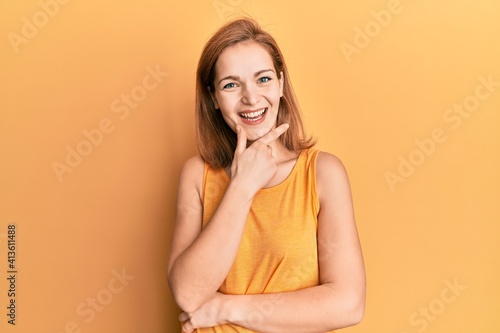 Young caucasian woman wearing casual style with sleeveless shirt looking confident at the camera smiling with crossed arms and hand raised on chin. thinking positive.