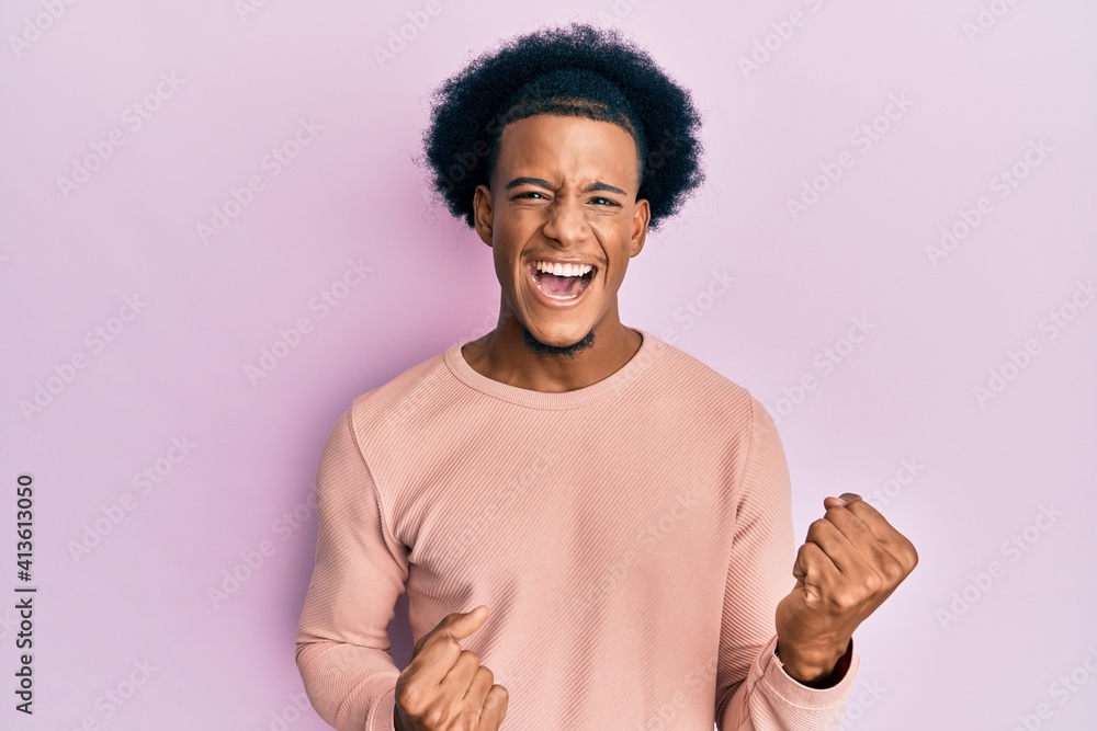 African american man with afro hair wearing casual clothes celebrating surprised and amazed for success with arms raised and eyes closed African american man with afro hair wearing casual clothes celebrating surprised and amazed for success with arms raised and eyes closed