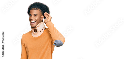 African american man with afro hair wearing cervical neck collar smiling with hand over ear listening an hearing to rumor or gossip. deafness concept. © Krakenimages.com