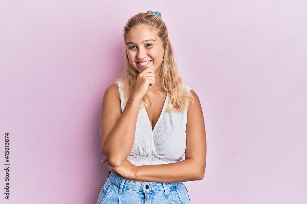 Young blonde girl wearing casual clothes looking confident at the camera smiling with crossed arms and hand raised on chin. thinking positive. Young blonde girl wearing casual clothes looking confident at the camera smiling with crossed arms and hand raised on chin. thinking positive.