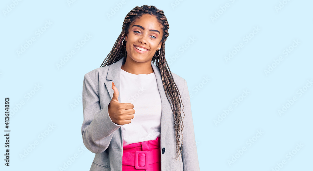 Young african american woman with braids wearing business clothes doing happy thumbs up gesture with hand. approving expression looking at the camera showing success. Young african american woman with braids wearing business clothes doing happy thumbs up gesture with hand. approving expression looking at the camera showing success.