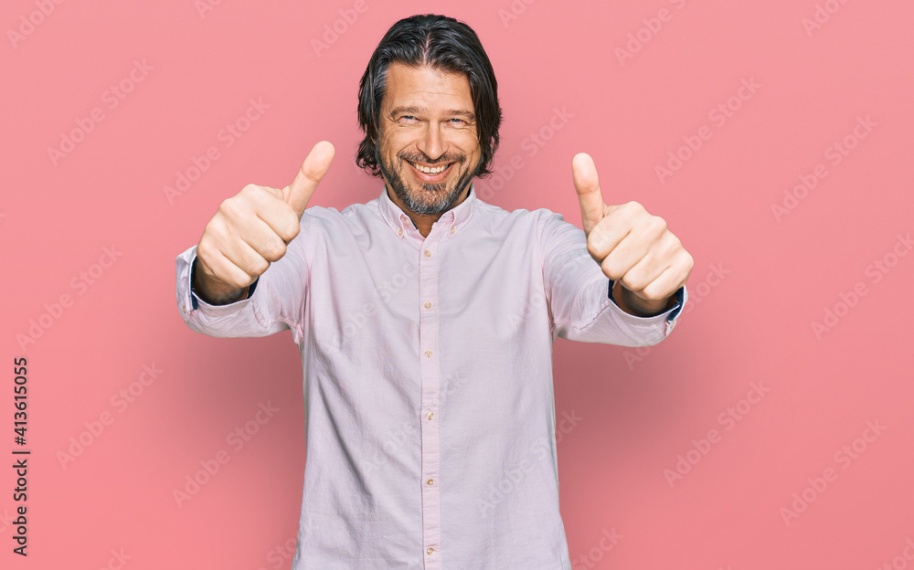 Middle age handsome man wearing business shirt approving doing positive gesture with hand, thumbs up smiling and happy for success. winner gesture.