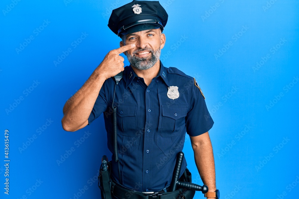 Middle age handsome man wearing police uniform pointing with hand finger to face and nose, smiling cheerful. beauty concept Middle age handsome man wearing police uniform pointing with hand finger to face and nose, smiling cheerful. beauty concept