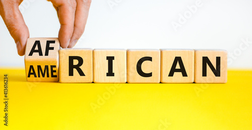 African american symbol. Businessman turns cubes with words 'african american'. Beautiful yellow table, white background. Business and african american concept. Copy space.