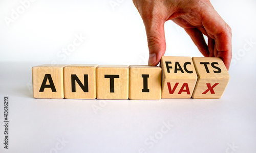 Anti-facts or anti-vax symbol. Doctor turns a cube, changes words 'anti-vax' to 'anti-facts'. Beautiful white background. Copy space. Business, medical covid-19 anti-facts or anti-vax concept. photo