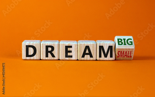 Dream small or big symbol. Turned wooden cubes and changed words 'dream small' to 'dream big'. Beautiful orange background, copy space. Business and dream small or big concept.