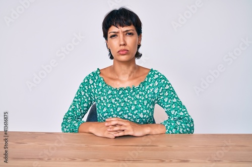 Beautiful brunettte woman wearing casual clothes sitting on the table depressed and worry for distress, crying angry and afraid. sad expression.