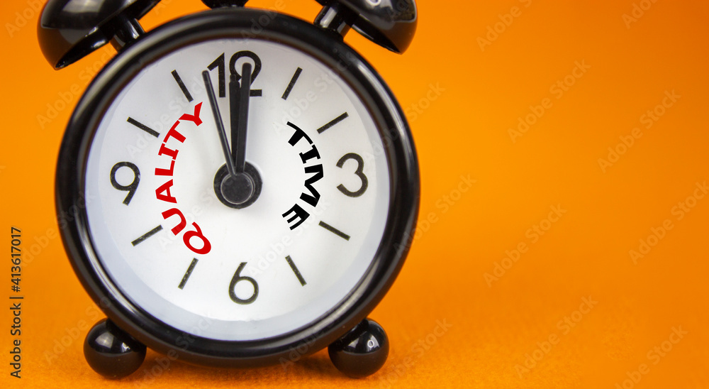 Quality time symbol. Beautiful black alarm clock with words 'quality time'. Beautiful orange background. Copy space. Business and quality time concept. Quality time symbol. Beautiful black alarm clock with words 'quality time'. Beautiful orange background. Copy space. Business and quality time concept.