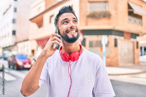 Young arab man smiling happy talking on the smartphone and using headphones at the city.