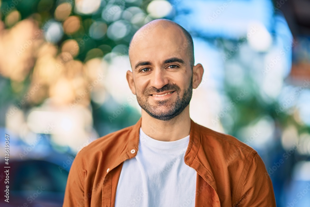 Fototapeta premium Young hispanic bald man smiling happy standing at the city.