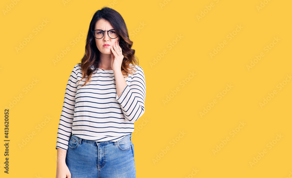 Beautiful young brunette woman wearing casual clothes and glasses touching mouth with hand with painful expression because of toothache or dental illness on teeth. dentist Beautiful young brunette woman wearing casual clothes and glasses touching mouth with hand with painful expression because of toothache or dental illness on teeth. dentist