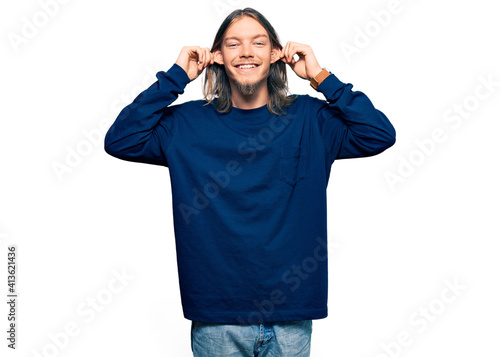 Handsome caucasian man with long hair wearing casual winter sweater smiling pulling ears with fingers, funny gesture. audition problem © Krakenimages.com