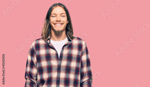 Handsome caucasian man with long hair wearing hipster shirt with a happy and cool smile on face. lucky person. © Krakenimages.com