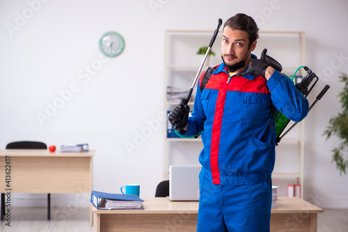 Young male contractor disinfecting office