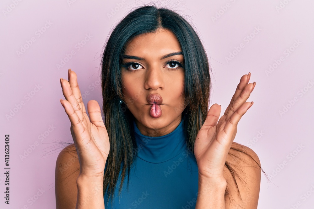 Young latin transsexual transgender woman with hands over face making fish face with mouth and squinting eyes, crazy and comical. Young latin transsexual transgender woman with hands over face making fish face with mouth and squinting eyes, crazy and comical.