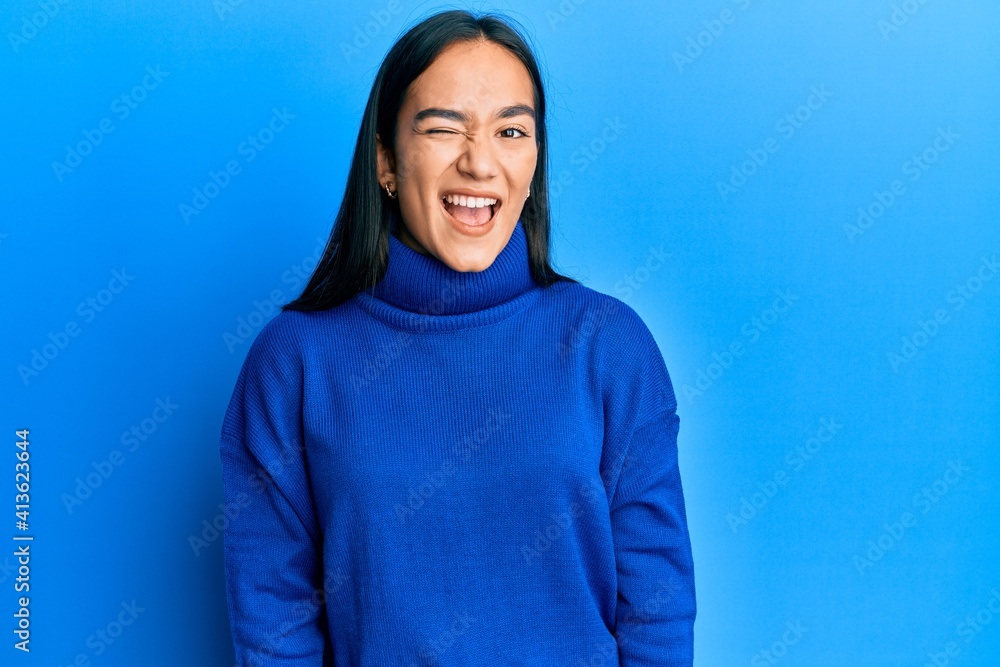 Young asian woman wearing casual winter sweater winking looking at the camera with sexy expression, cheerful and happy face. Young asian woman wearing casual winter sweater winking looking at the camera with sexy expression, cheerful and happy face.